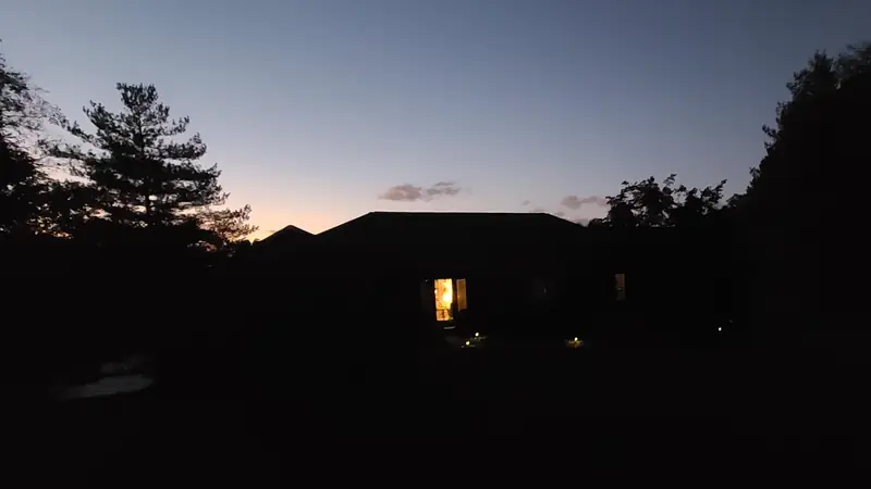 Ranch house after dark with only a lit doorway showing, the rest of the house in shadow