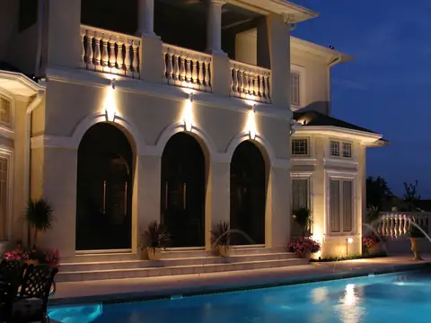 Pool and fountain below a lit stucco loggia with arched openings